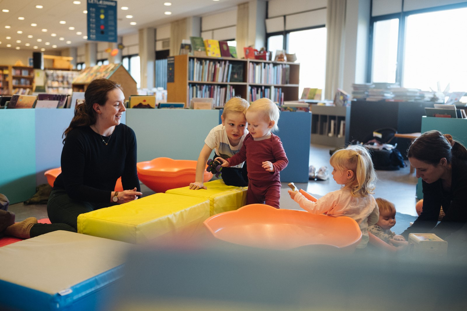 To kvinder med fire mindre børn leger med skumpudder og store snurretoppe på Vejle Bibliotek. Foto: Jonas Normann